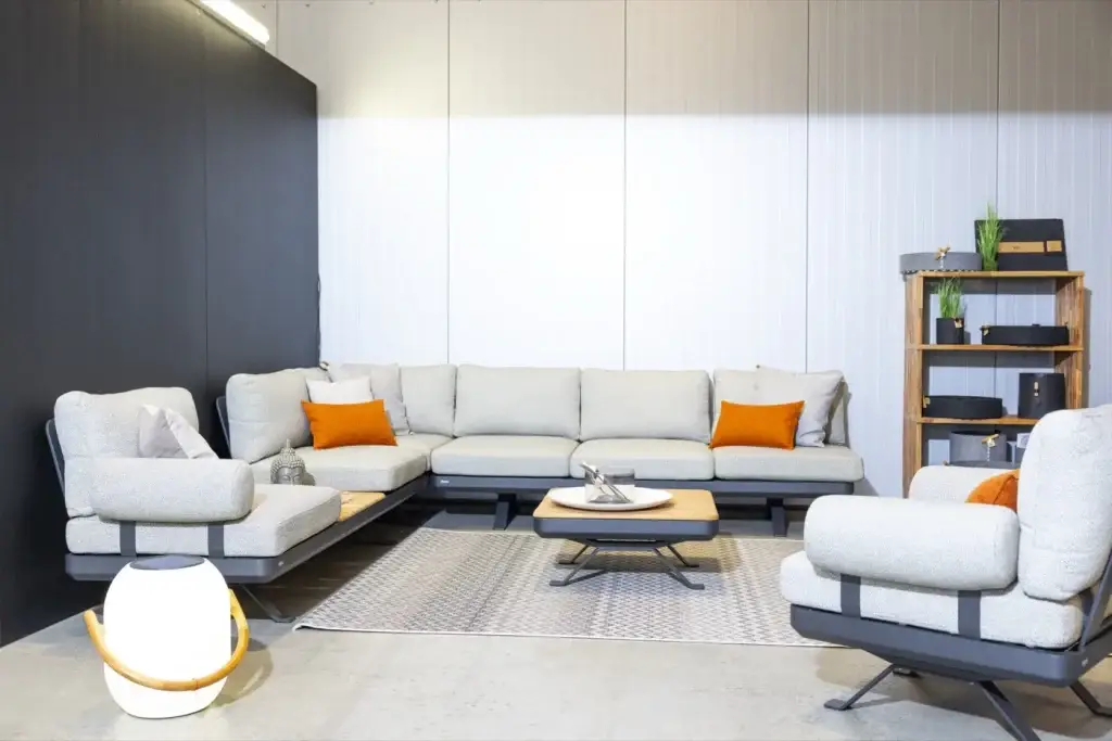 Helle Lounge-Ecke mit orangen Kissen, Sessel und Couchtisch in der Ausstellung von Trendhouse in Fulda