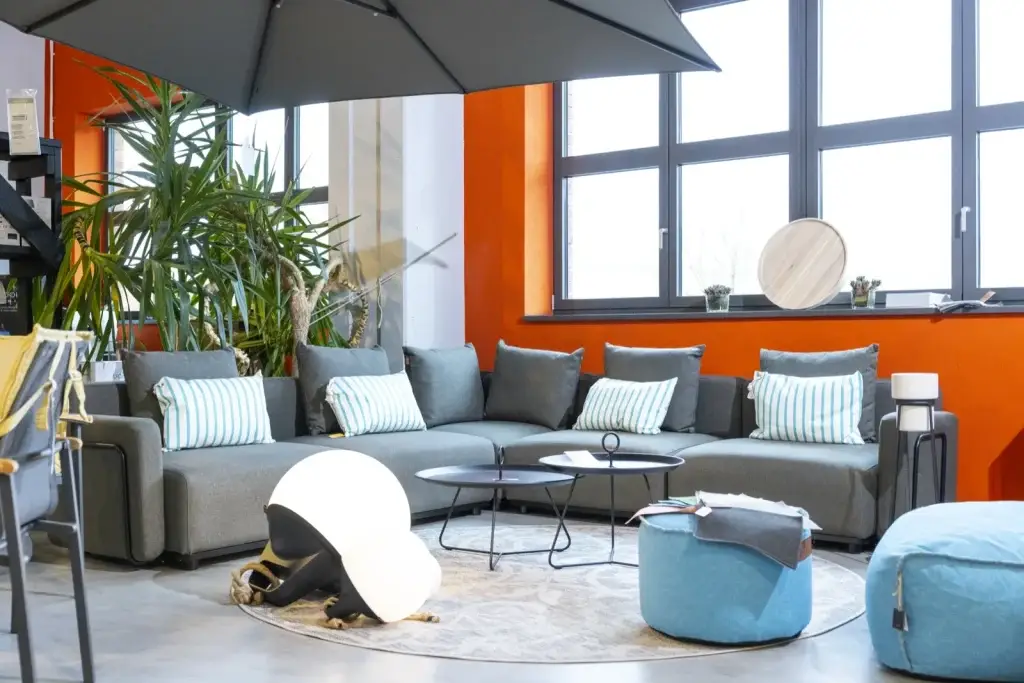 Großer Sonnenschirm über einer grauen Lounge-Gruppe vor oranger Wand bei Trendhouse in Fulda